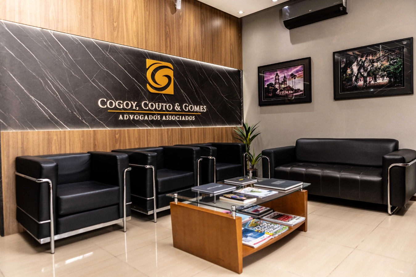 Recepção do escritório CCG com poltronas de couro preto, mesa de centro com revistas e logotipo retroiluminado na parede.